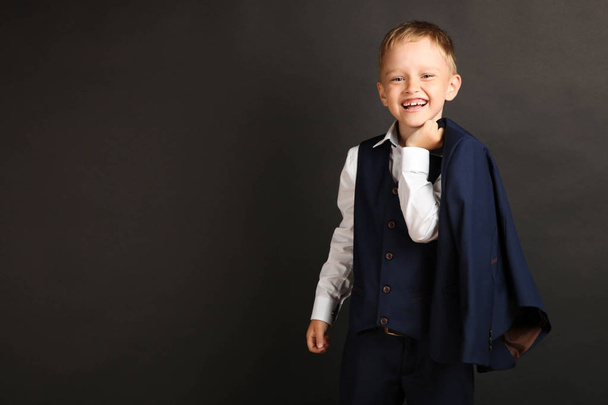 Joyful schoolboy in school uniform on black background. Concept school. - Foto, Bild