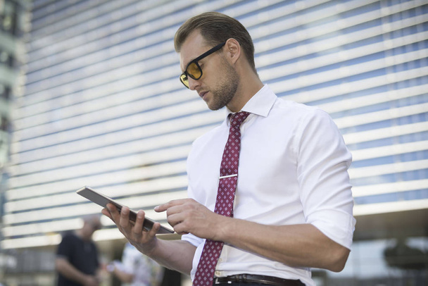 Businessman using a tablet outdoors - Foto, afbeelding