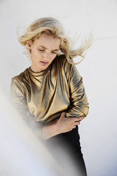 Beautiful windswept blond girl in gold fashion, looking down - Foto, Imagem