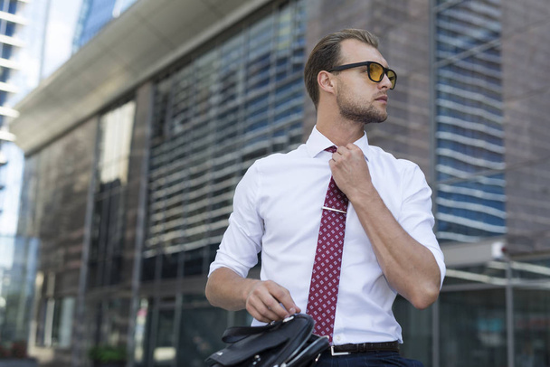 Employee adjusting his necktie, preparing for a meeting in the city  - Foto, imagen