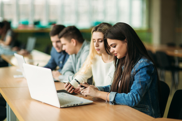 Grupo de estudantes universitários que estudam na biblioteca da escola, uma menina e um menino estão usando um laptop e se conectando à internet
 - Foto, Imagem