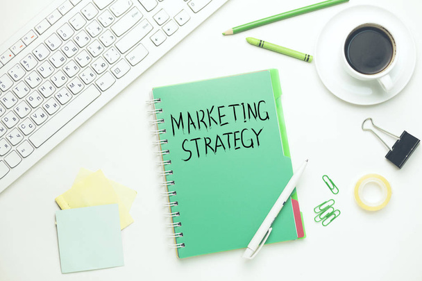 marketing strategy text on notebook with keyboard and stationary on table - Zdjęcie, obraz