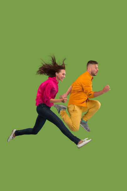 Freedom in moving. Pretty young couple jumping against green background - Photo, Image