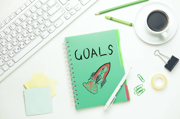 goals text on notebook with keyboard and stationary on table - 写真・画像