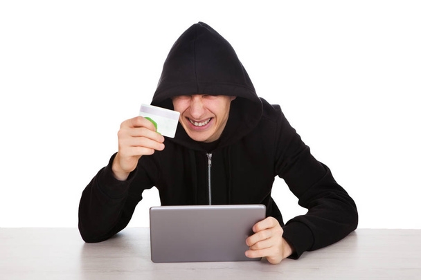 Cheerful Hacker with a Tablet Computer and Bank Card on the White Background - Fotó, kép