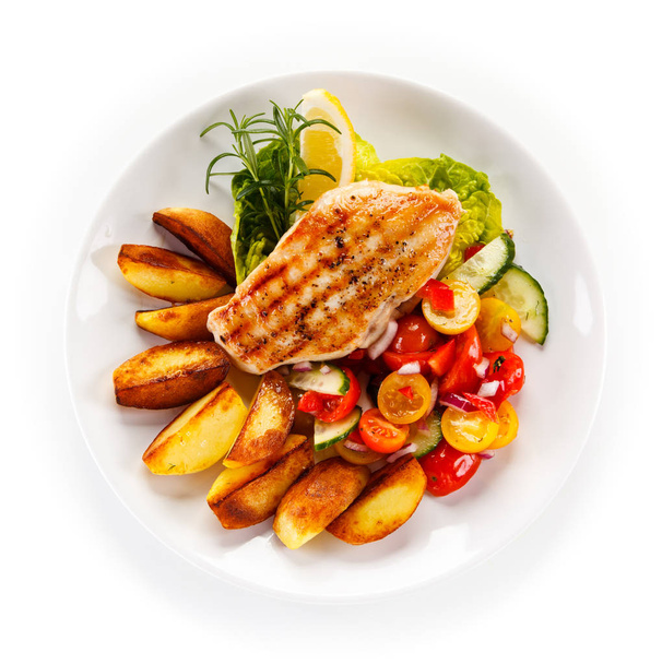 Top view of grilled chicken fillet with baked potatoes and fresh salad on plate isolated on white background - Foto, Bild