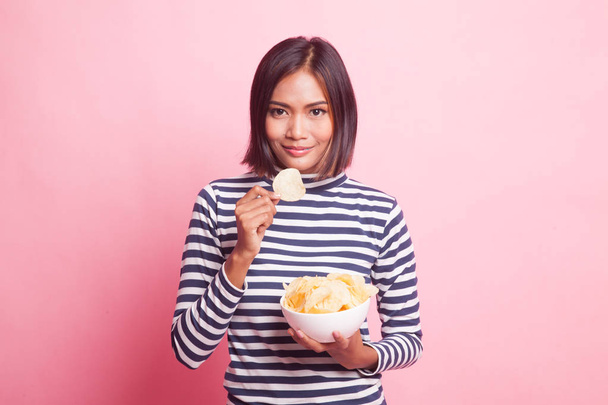 Young Asian woman eat potato chips on pink background - Foto, Imagem