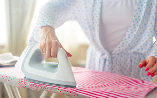 Closeup of woman ironing clothes ironing board - Foto, imagen