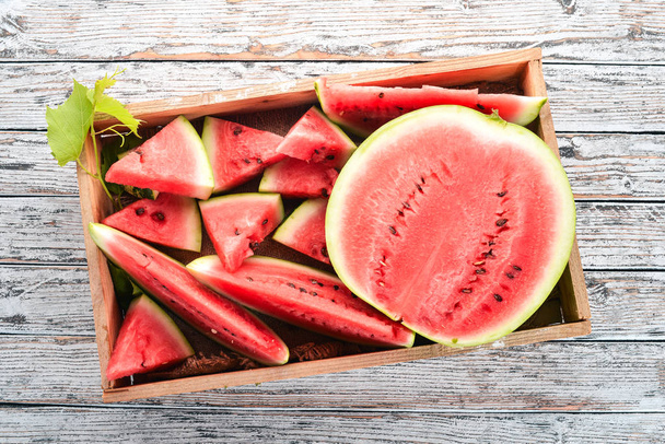 Watermelon in a wooden box. Sliced to pieces of watermelon. On a wooden background. Free space for text. Top view. - Fotoğraf, Görsel