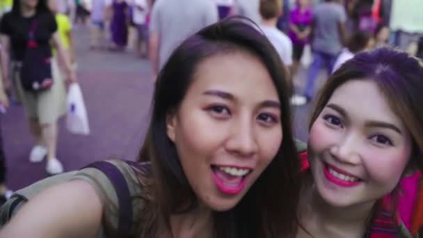 Viajero mochilero blogger Asiático mujeres lesbianas lgbt pareja viajar usando smartphone para selfie en Tailandia. Beber alcohol femenino o cerveza en Khao San Road la calle más famosa de Bangkok
. - Imágenes, Vídeo
