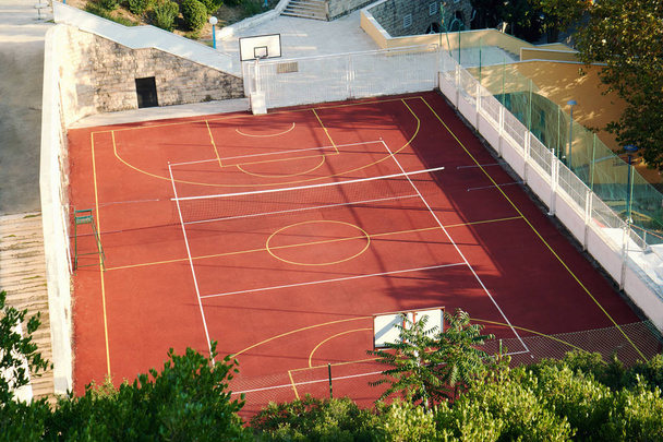 Baloncesto al aire libre y pista de tenis con arcilla roja. Vista desde arriba
 - Foto, imagen