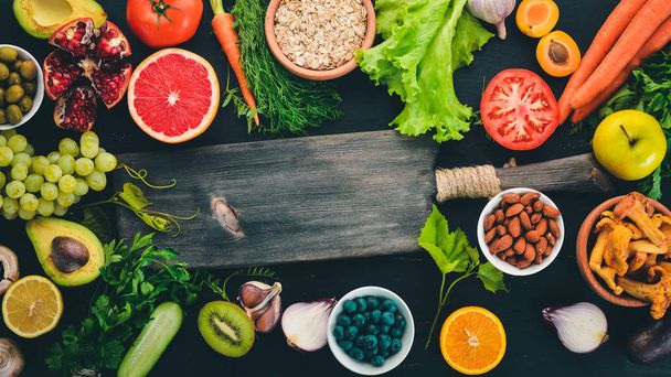 Καθαρά Τρώτε ποικιλία υγιεινών τροφίμων: λαχανικά, φρούτα, ξηροί καρποί, μούρα και μανιτάρια, μαϊντανό, μπαχαρικά. Σε μαύρο φόντο. Ελεύθερο χώρο για το κείμενο. - Φωτογραφία, εικόνα
