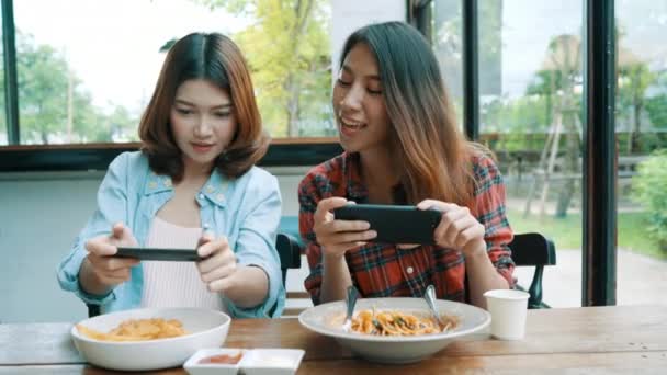 Felices hermosas amigas asiáticas bloguera usando foto de teléfono inteligente y haciendo video vlog comida para sus suscriptores y su canal en la cafetería
. - Metraje, vídeo