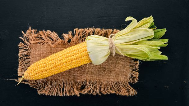 Fresh yellow corn on a black wooden table. Vegetables. Top view. Copy space. - Foto, Bild