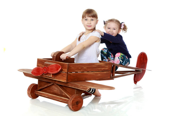 two sisters playing in a wooden plane - Фото, зображення