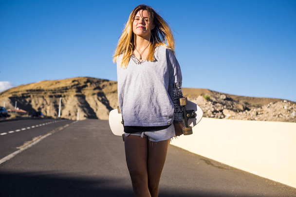 молодая женщина держит скейтборд, активный отдых на открытом воздухе и альтернативный образ жизни
 - Фото, изображение