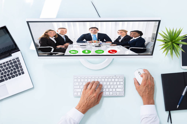 Elevated View Of A Businessman's Hand Videoconferencing With Colleagues On Computer - Zdjęcie, obraz