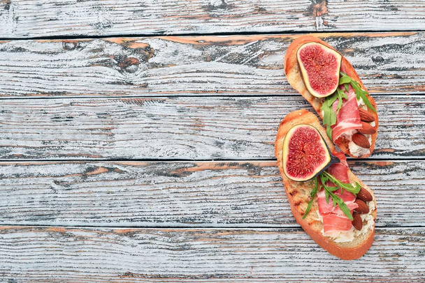 Sandwich with figs, prosciutto and cheese. On the old background. Healthy food. Free space for text. Top view. - Foto, afbeelding