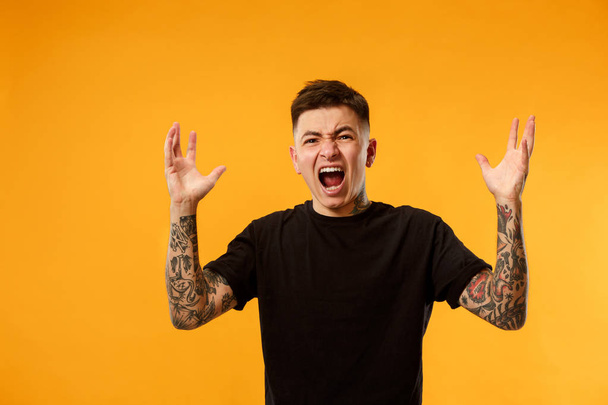 The young emotional angry man screaming on studio background - Photo, Image