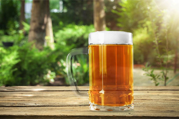Mug of cold beer on wooden table  - Фото, изображение