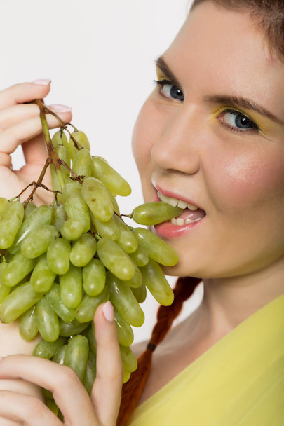Beautiful redhead woman is eating grapes. concept of healthy eating - Fotó, kép