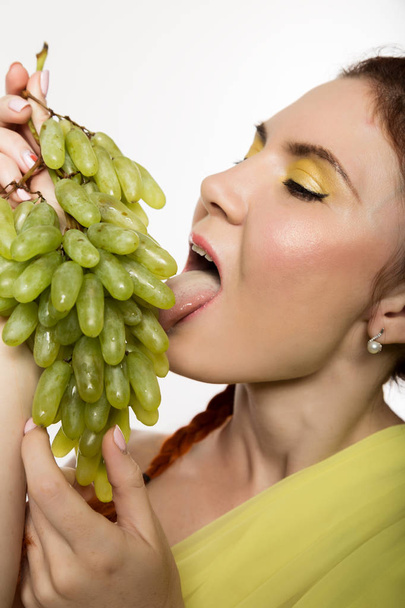 Beautiful redhead woman is eating grapes. concept of healthy eating - Foto, Imagem