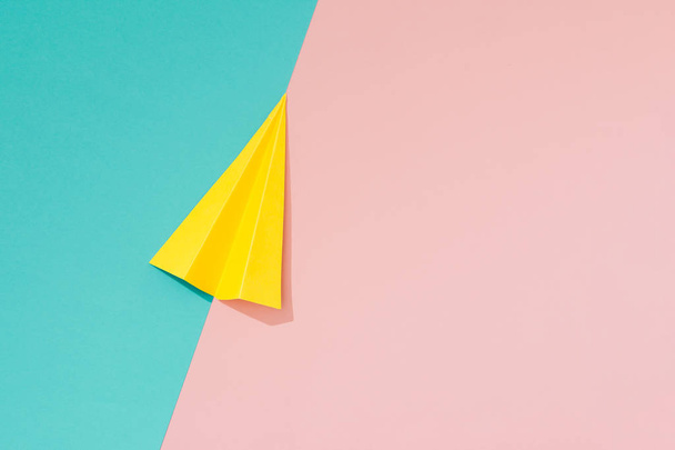 Yellow paper airplane on pastel pink and blue background. Minimal flat lay school concept - Photo, Image