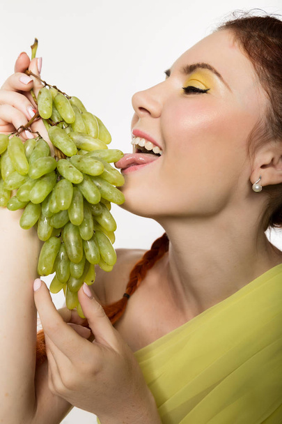 Beautiful redhead woman is eating grapes. concept of healthy eating - Fotoğraf, Görsel