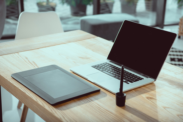 portátil con pantalla en blanco y tableta gráfica en la mesa de madera en la oficina
 - Foto, imagen