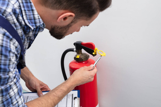 Young Male Technician Checking Symbol On Fire Extinguisher - Fotoğraf, Görsel