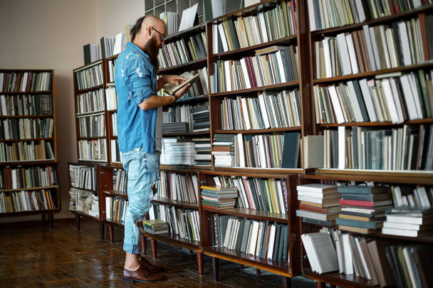 Po celé délce portrét stylový vousatý muž čtení knihy v knihkupectví nebo v knihovně. Koncepce vzdělávání  - Fotografie, Obrázek