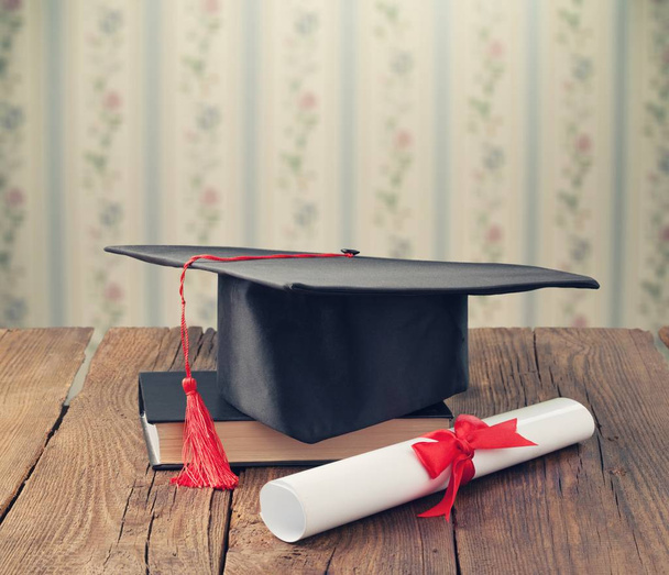 Graduation hat, book and diploma on table - Foto, imagen