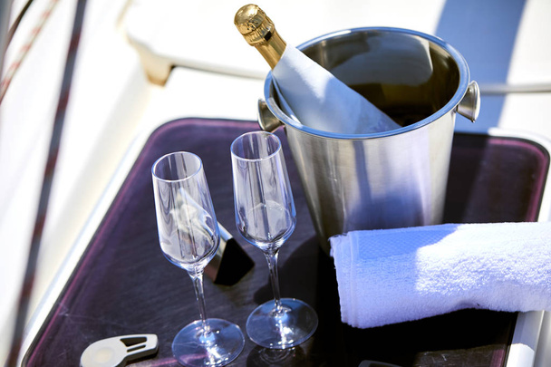 Coppia di bicchieri di champagne e secchio con bottiglia di champagne su yacht
 - Foto, immagini