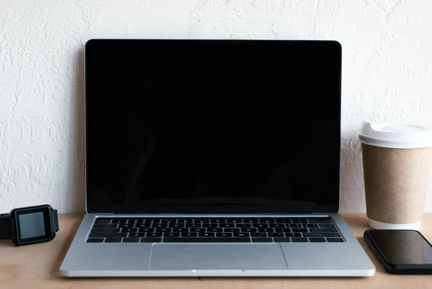 laptop with blank screen, smartwatch, smartphone and coffee to go on table - Zdjęcie, obraz