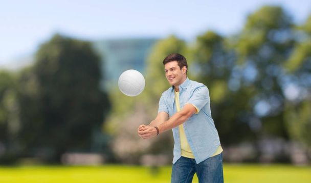 smiling man playing volleyball over summer par - Photo, Image