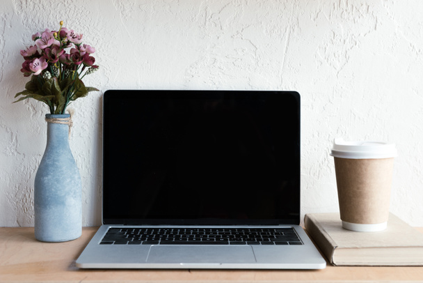laptop-val üres képernyő, virágok vázában, könyv, kávé, tovább a táblázat - Fotó, kép
