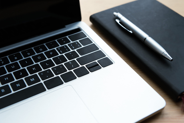 vista close-up de laptop, notebook e caneta na mesa de madeira
 - Foto, Imagem