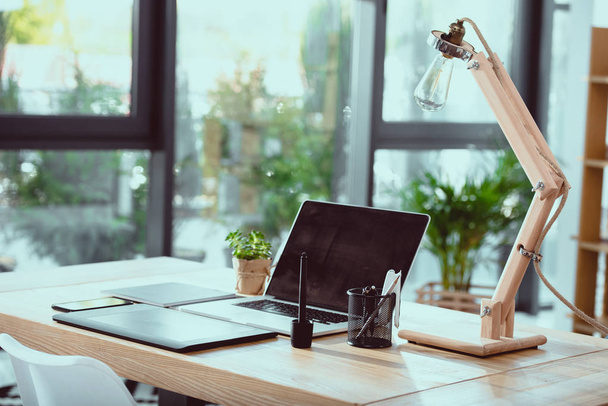 Laptop mit Grafik-Tablet und Lampe mit Büroanbietern am Arbeitsplatz - Foto, Bild