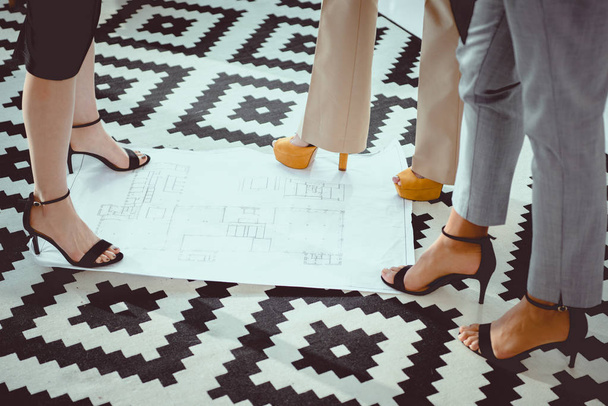 cropped shot of women on high heels shoes standing on blueprint - Photo, Image
