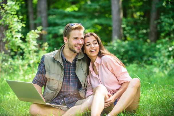 Couple youth spend leisure outdoors with laptop. Man and girl working with laptop at green meadow. Modern technologies give opportunity to work in any environment conditions. Freelance opportunity - Photo, image