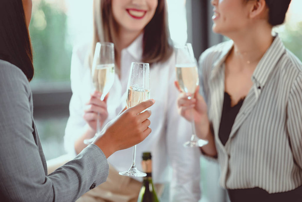 tiro cortado de mulheres de negócios em uso formal bebendo champanhe dentro de casa
 - Foto, Imagem