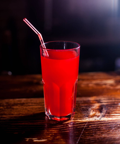 roter Juse auf einem Tisch, dunkler Hintergrund - Foto, Bild
