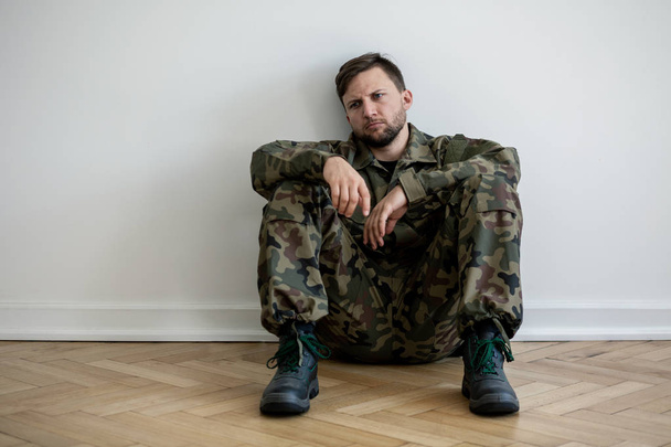 Sad and lonely soldier in green uniform with depression and war syndrome - Фото, изображение