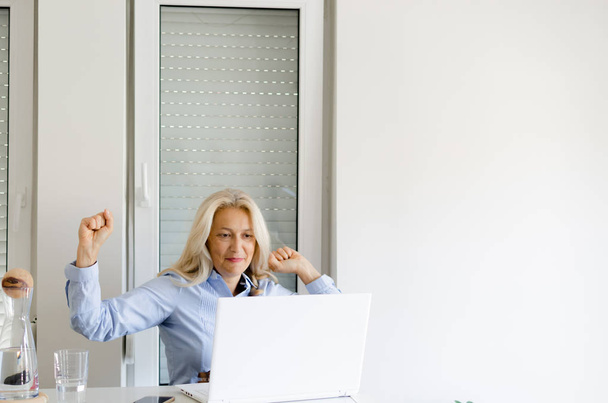 Retrato de la mujer mayor olorosa con las manos arriba trabajando en casa en el ordenador portátil, espacio para el texto
. - Foto, Imagen