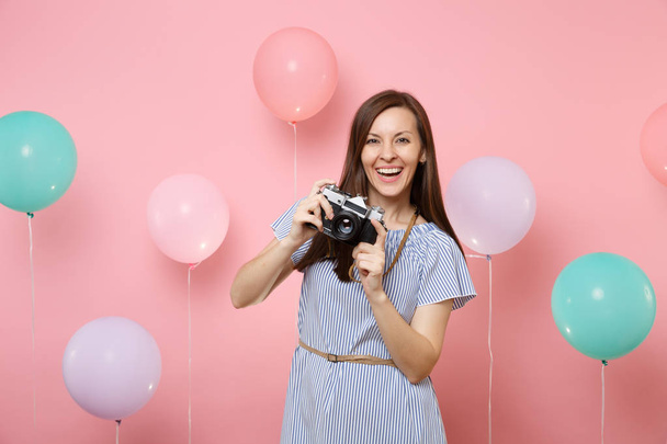 Mavi elbiseli retro vintage fotoğraf kamera renkli hava balonları ile parlak pembe arka plan üzerinde tutarak büyüleyici genç mutlu kadın portresi. Doğum günü tatil parti insanlar samimi duygular kavramı - Fotoğraf, Görsel