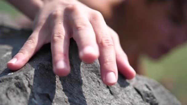 de klimmer klimt op de rotsen. Het bereiken van hoogte, een extreme sport. Hand close-up. - Video