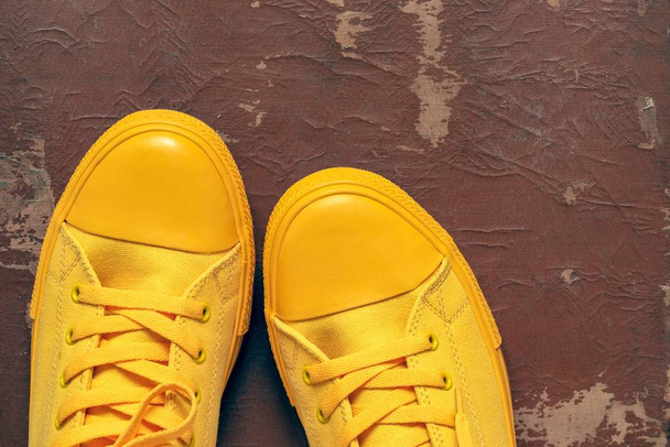 yellow fashionable gym shoes or sports boots closeup against the background of old brown skin - Photo, Image