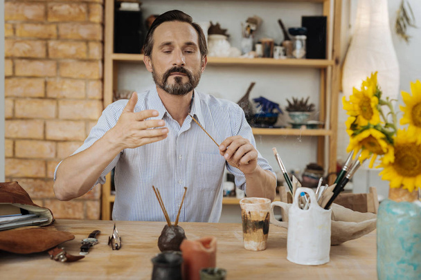 Dark-haired creative man searching inspiration in his workshop - Photo, Image
