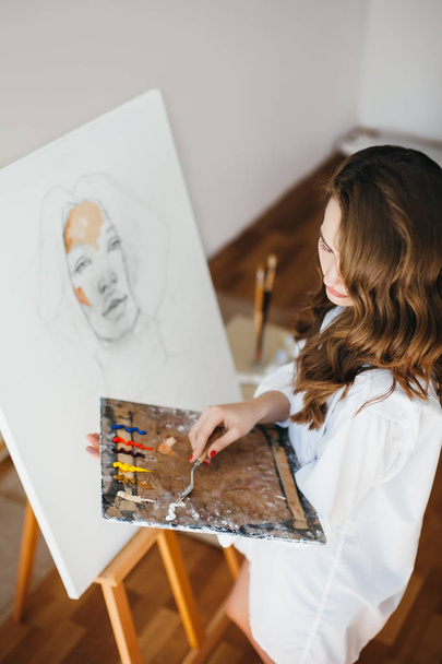 Young female painter at artwork process. Artist painting artwork - Foto, Bild