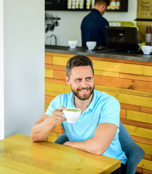 Cafe visitor happy smiling face enjoy coffee drink. Improve overall health. Take moment to care about yourself. Coffee drinkers live longer. Man bearded guy drinks cappuccino wooden table cafe - 写真・画像